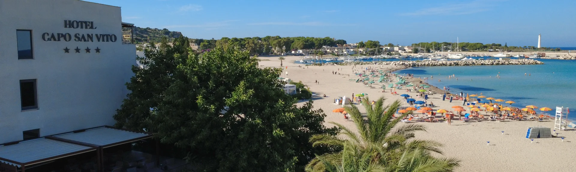 Hotel Capo San Vito overlooking a sandy beach with umbrellas and sea